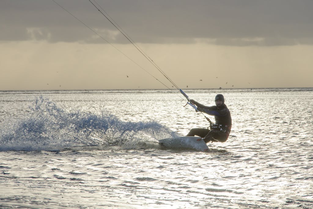 A thrilling kiteboarding scene against a picturesque sunset backdrop, capturing the excitement of water sports.