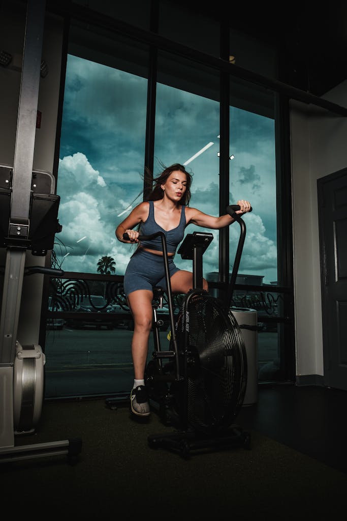 A woman works out on a stationary bike indoors, promoting fitness and health.