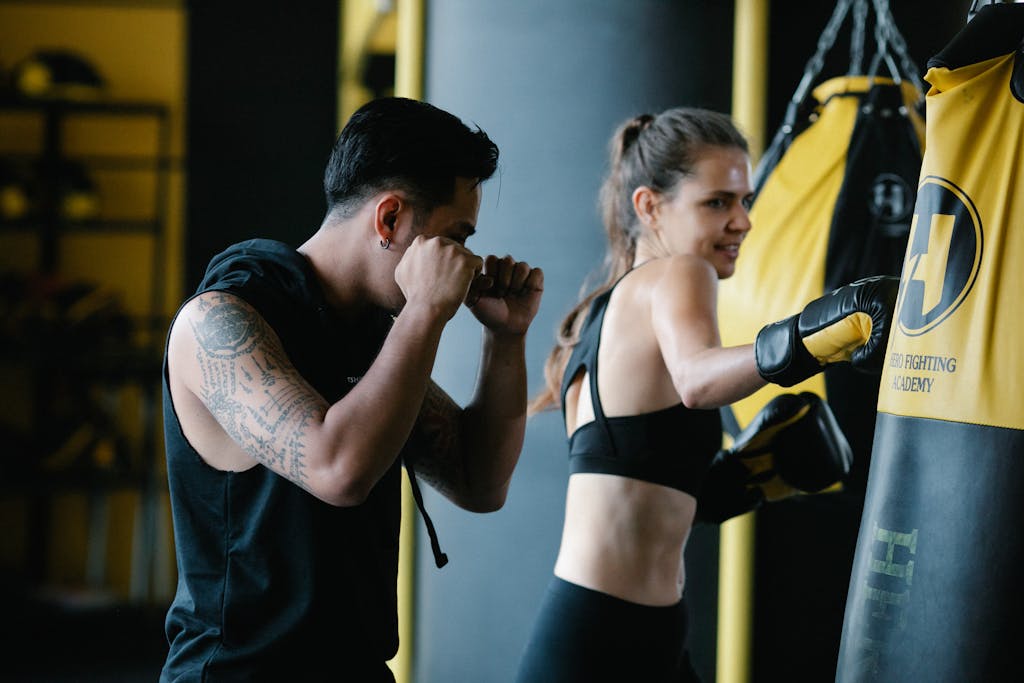 Focused boxing practice with trainer and trainee in a modern gym setting.