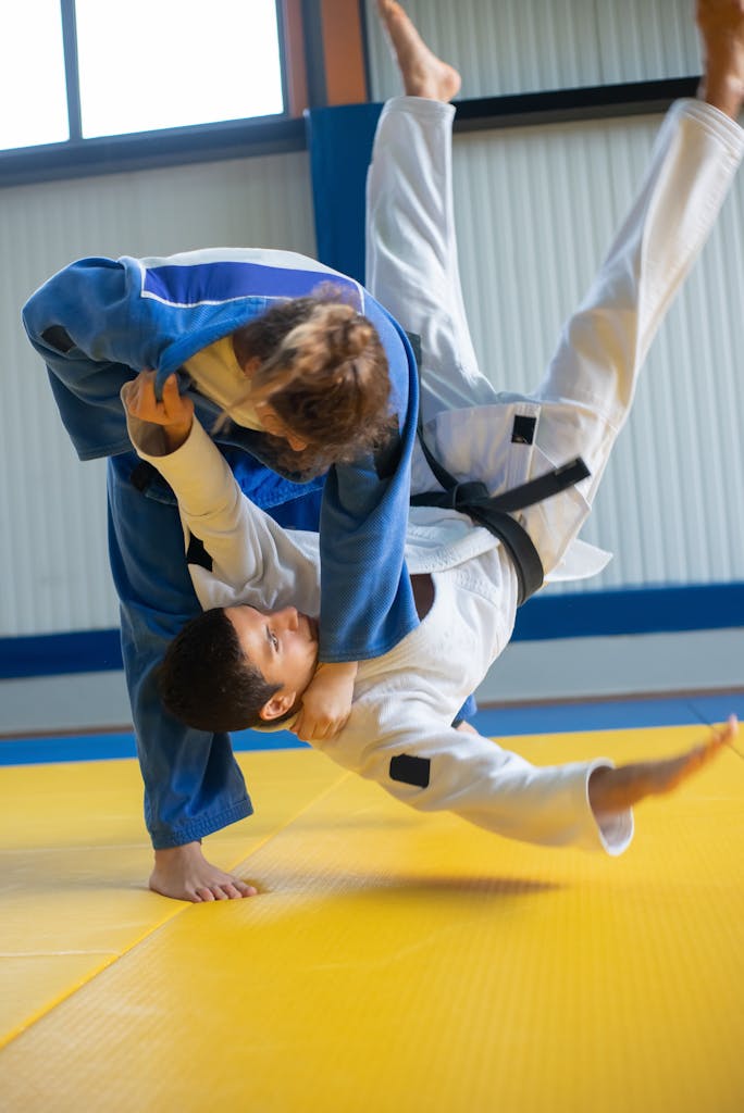Two judokas in intense training, executing a dynamic throw on a dojo mat.